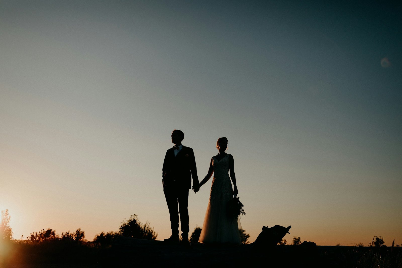 Bride and groom holding hands at sunset